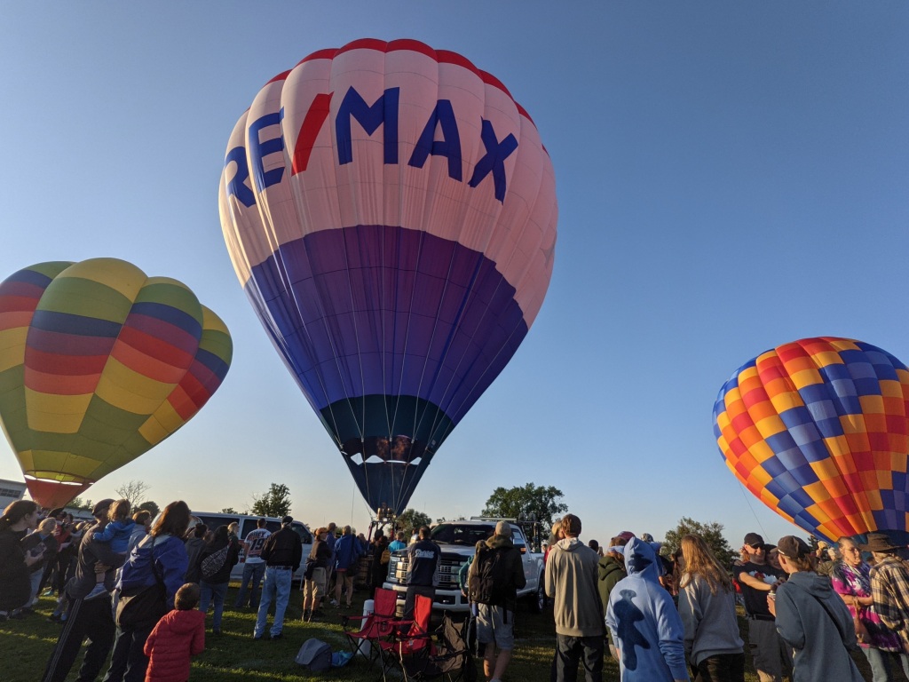 Three inflated hot air balloons. The center balloon features a Remax logo.